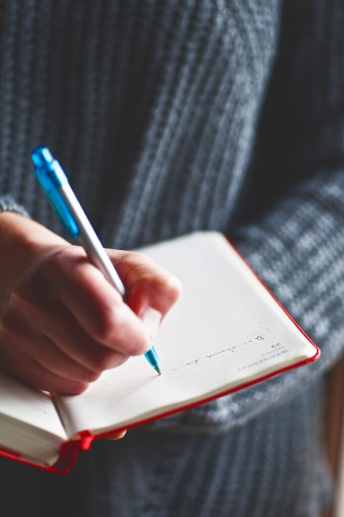 Person writing in a journal or book, symbolizing personal storytelling, reflection, and documenting human rights experiences
