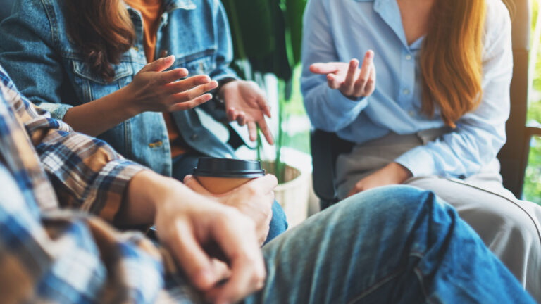 Group of people in conversation, showing hands and torsos, symbolizing connection and shared dialogue about human rights